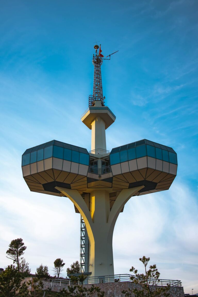 Striking telecommunication tower in Podgorica against a vibrant blue sky.